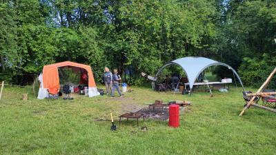 Spejderlejr med køkkentelt, partytelt, bålplads med vandslukker og grillriste